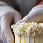 Close-up of a pastry chef meticulously decorating a cake with edible flowers