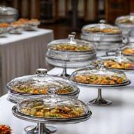 Elegant serving platters and cloches on a catering display table, ready for food service.