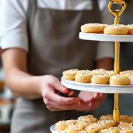 A professional Flourish & Crumb catering team member meticulously arranging patisserie on a display.